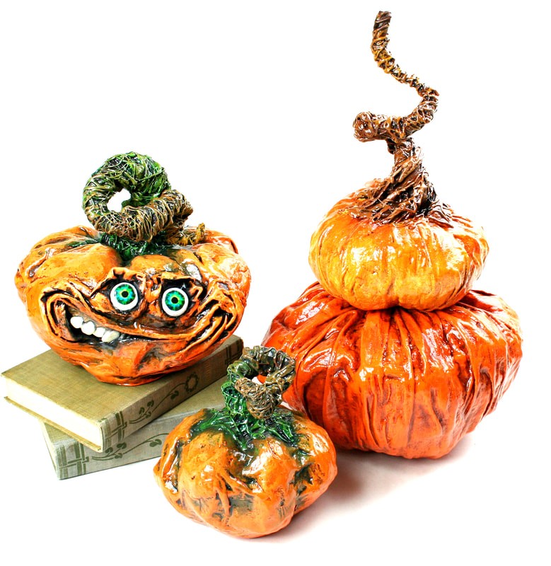 Jessica Dvergsten paper mache sculptures of a orange halloween jack o lantern grinning with three orange pumpkins.